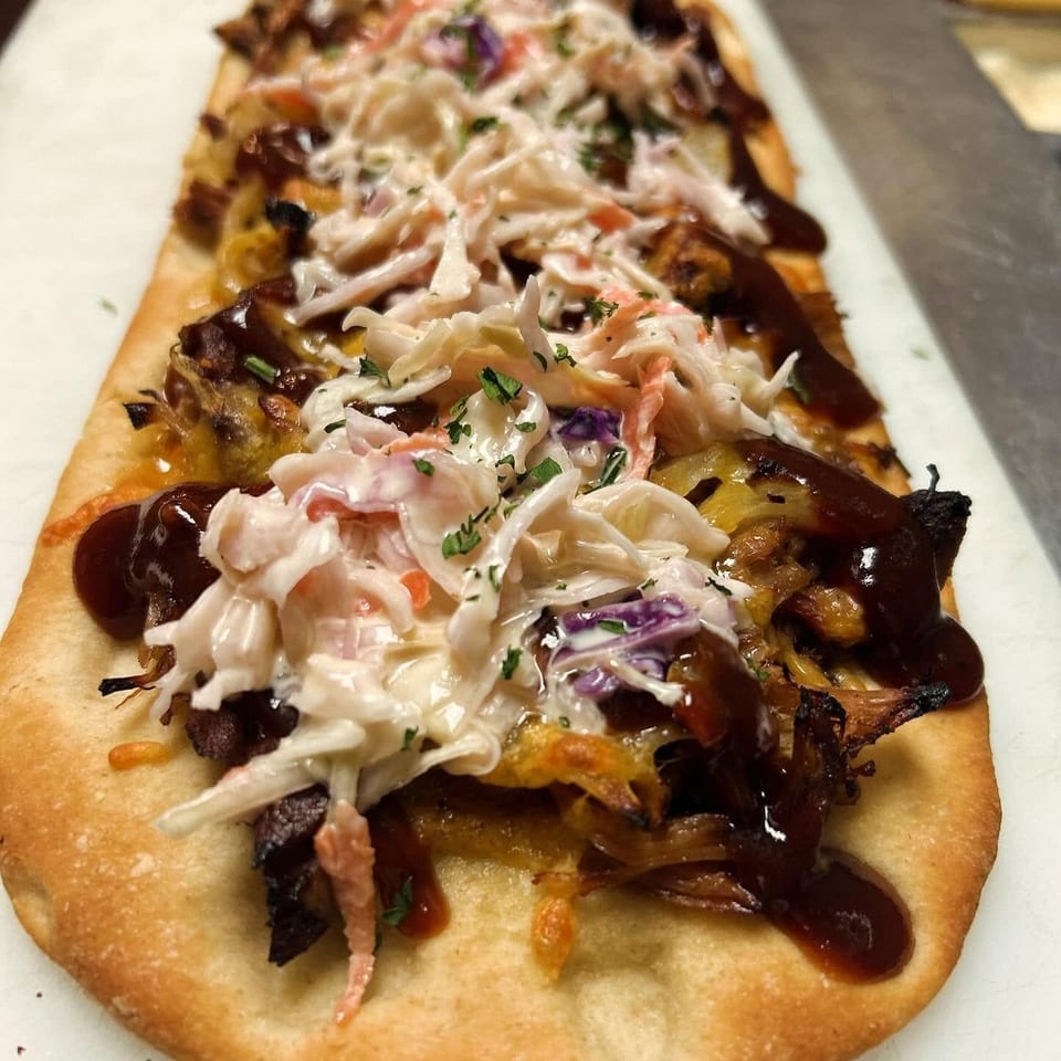 Flatbread topped with pulled pork, melted cheese, barbecue sauce, and creamy coleslaw.