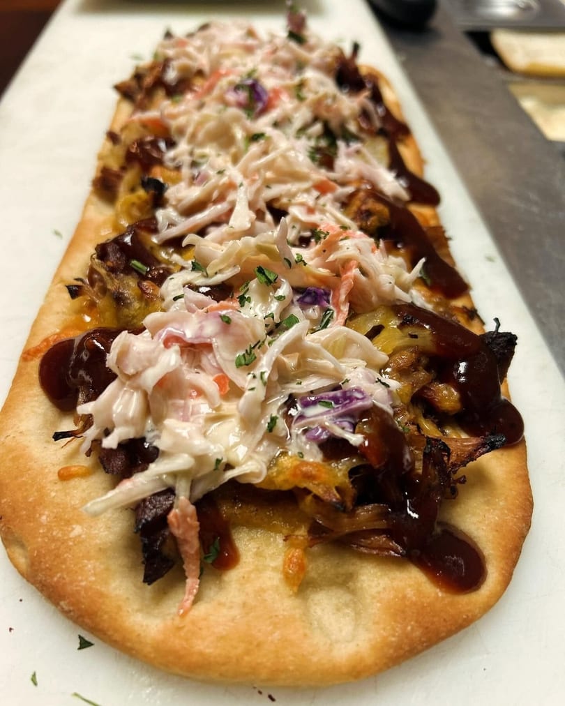 Flatbread topped with pulled pork, melted cheese, barbecue sauce, and creamy coleslaw.